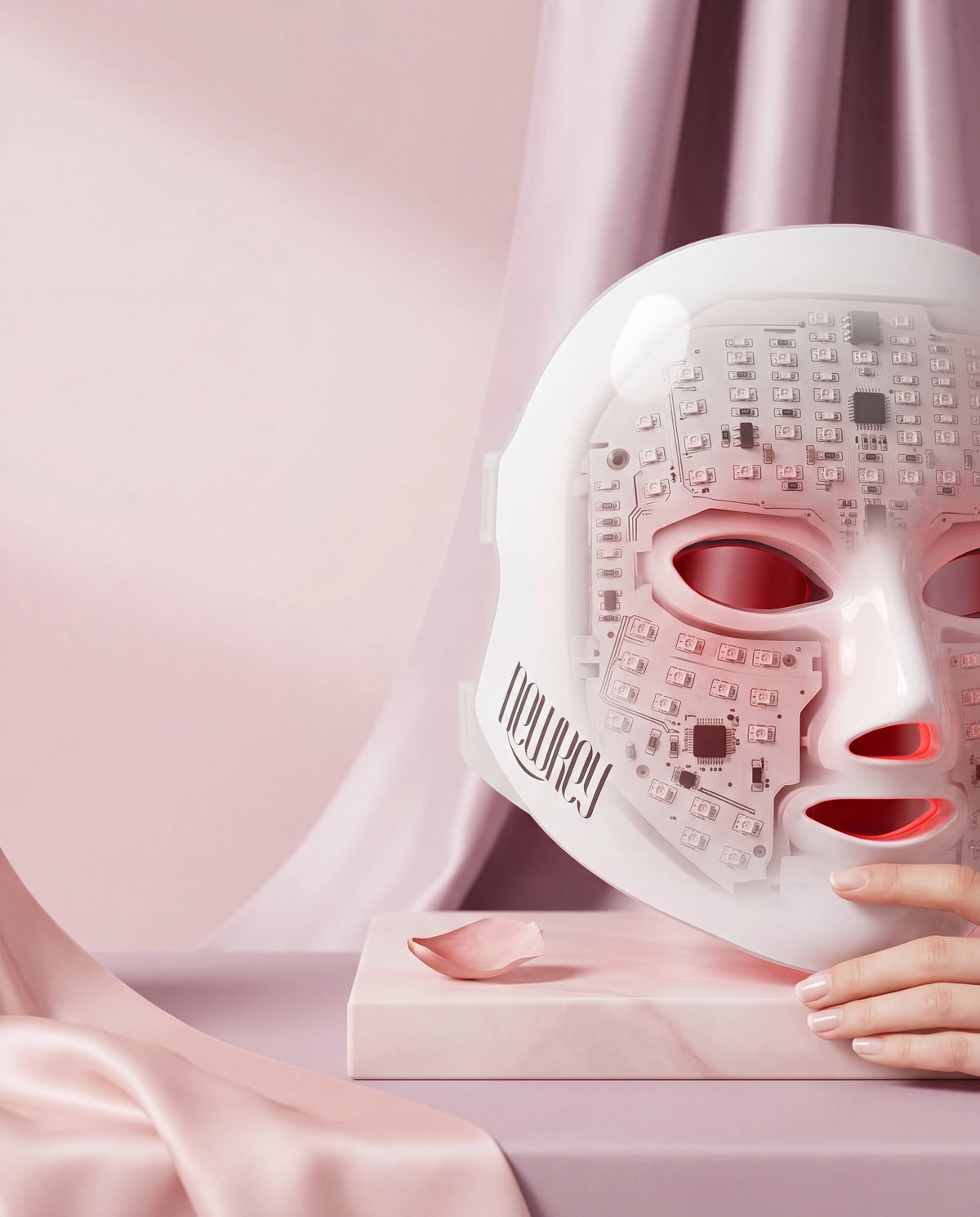 NEWKEY 4D LED Therapy Mask shown in a high-key studio photograph, with soft light emphasizing its glowing interior. Blush pin